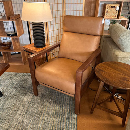 Brown leather armchair in a room with wooden furniture and decor.