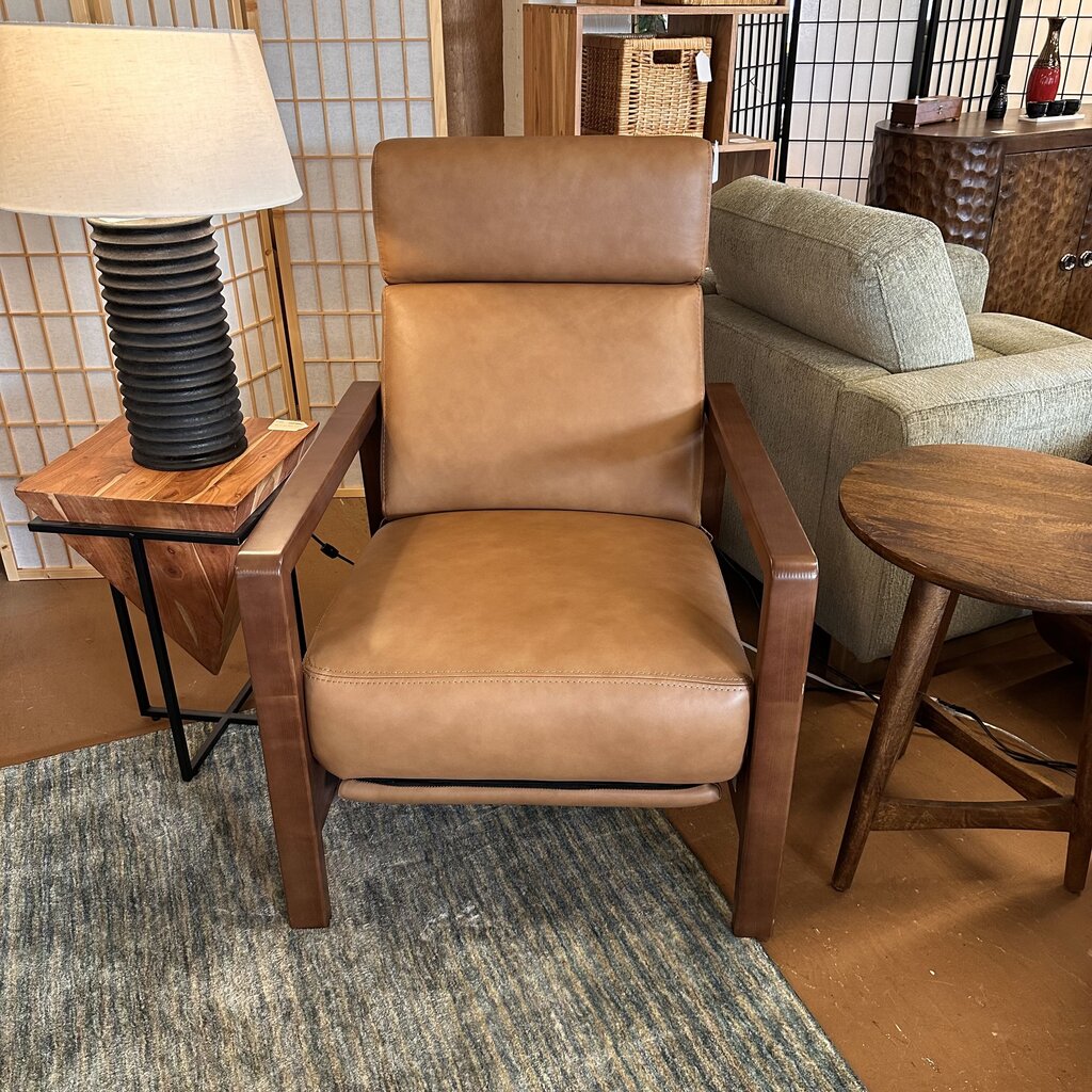 Brown leather armchair in a room with a lamp and side table.