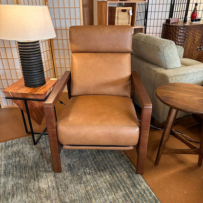 Brown leather armchair in a room with a lamp and side table.