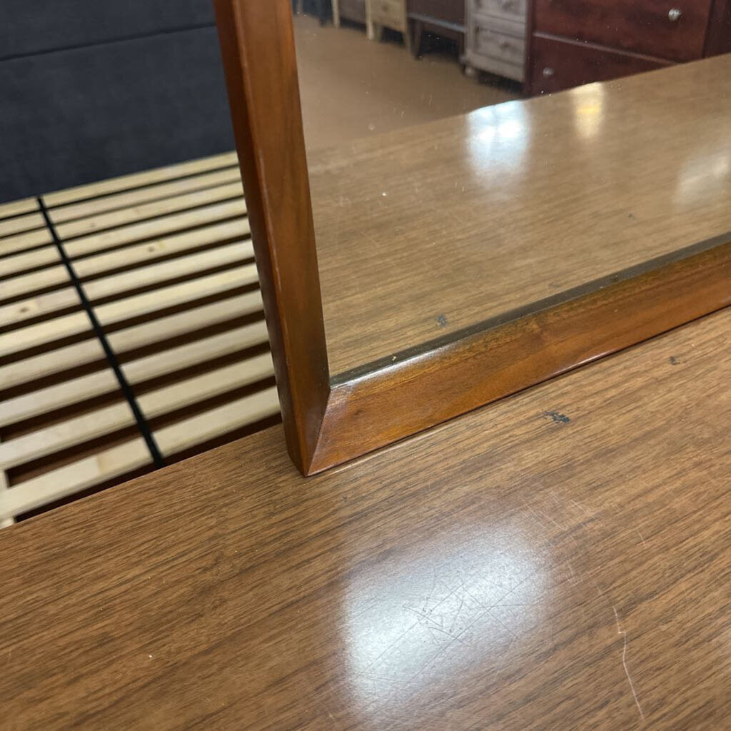Wooden surface with a mirror reflecting a room interior.