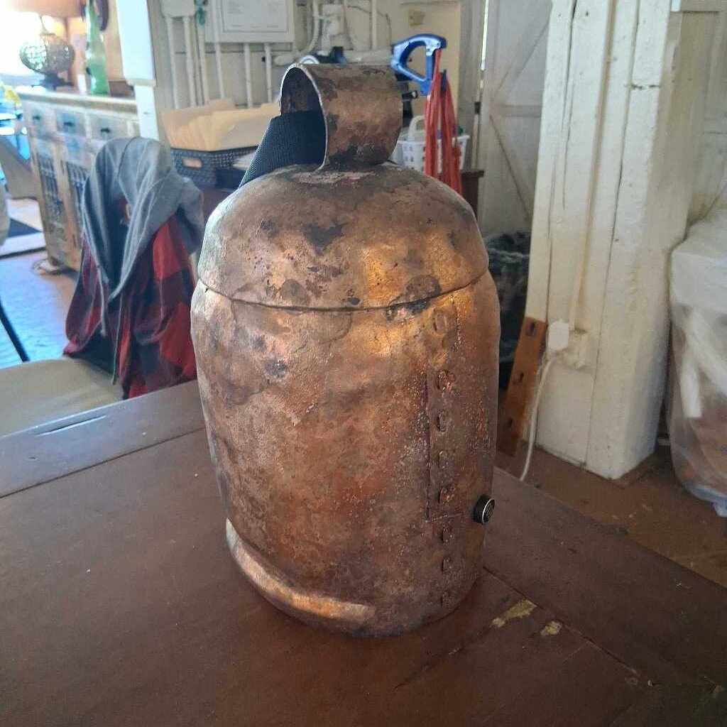 Rust-covered metal container on a wooden surface with a cluttered background