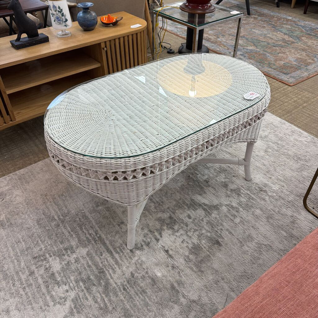 Wicker coffee table with glass top on a carpeted floor
