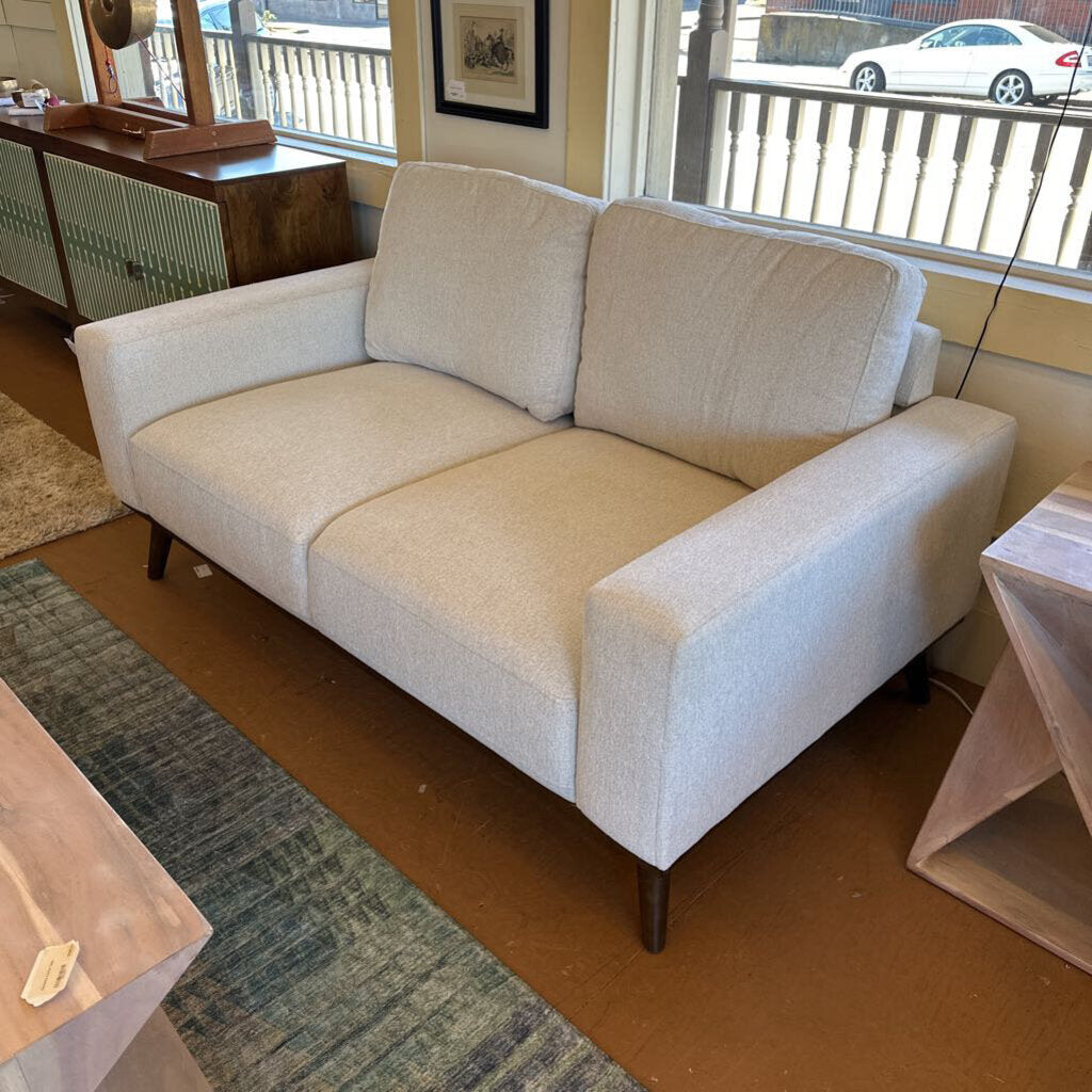 Beige sofa in a room with a rug and window