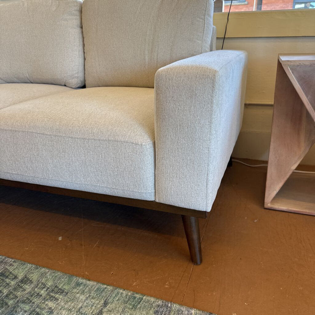 Beige sofa with wooden legs in a room setting