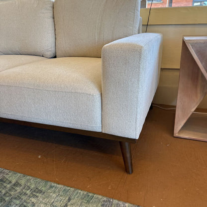 Beige sofa with wooden legs in a room setting