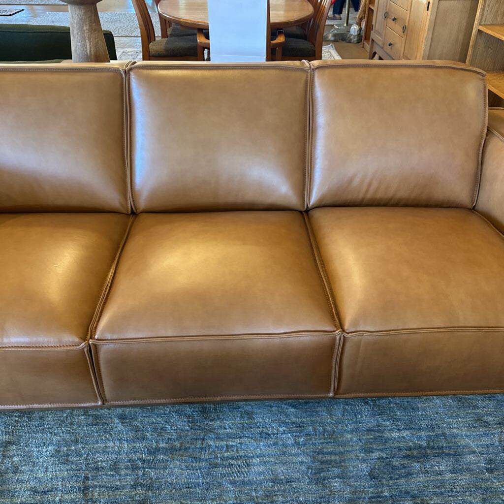 Brown leather sofa on a blue carpet with a blurred indoor background