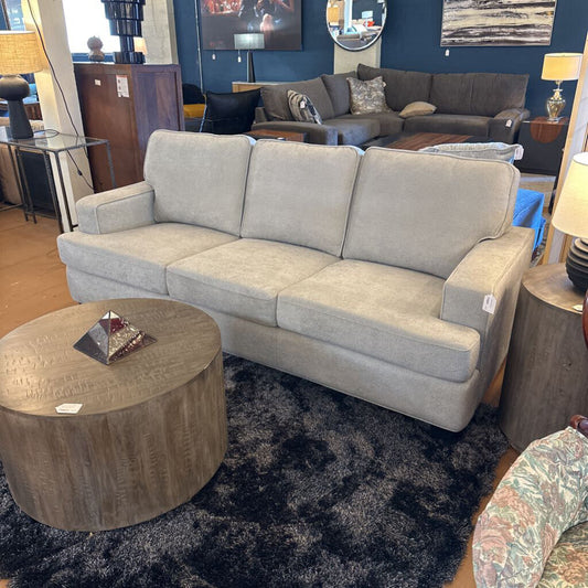 Gray sofa in a room with a round coffee table and other furniture.