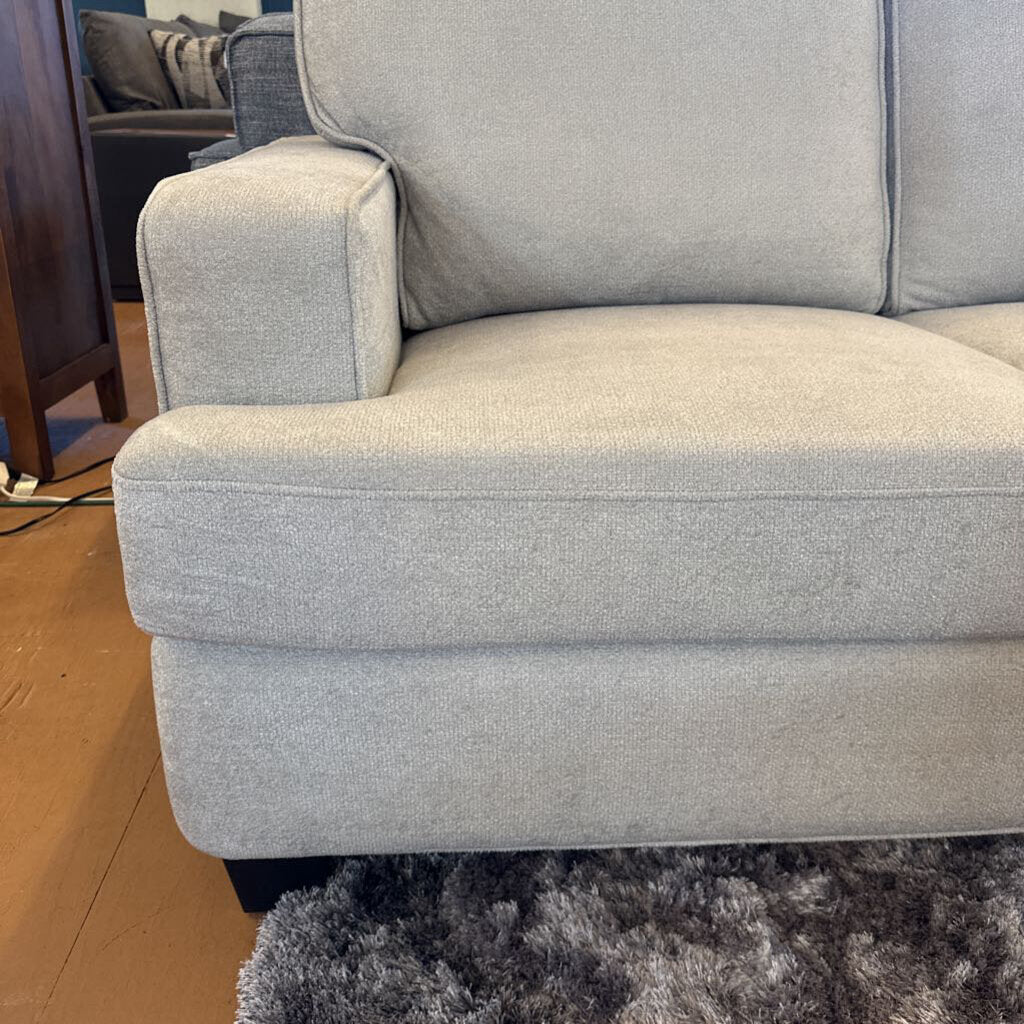 Gray sofa in a room with wooden flooring and a rug.