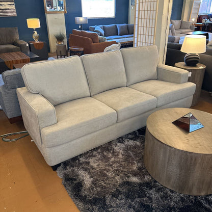 Beige sofa in a living room setting with other furniture and decor.