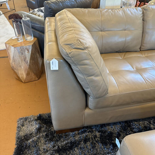 Beige leather sofa with a price tag in a showroom setting