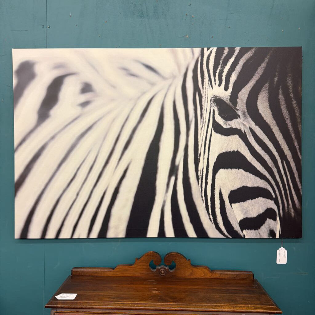 Zebra painting on a teal wall above a wooden piece of furniture