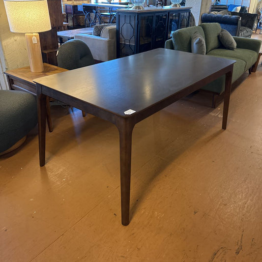 Wooden dining table in a room with chairs and a lamp.