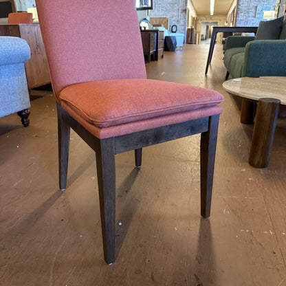 Chair with pink cushion on a wooden floor in a showroom setting