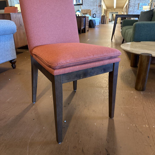 Chair with pink cushion on a wooden floor in a showroom setting