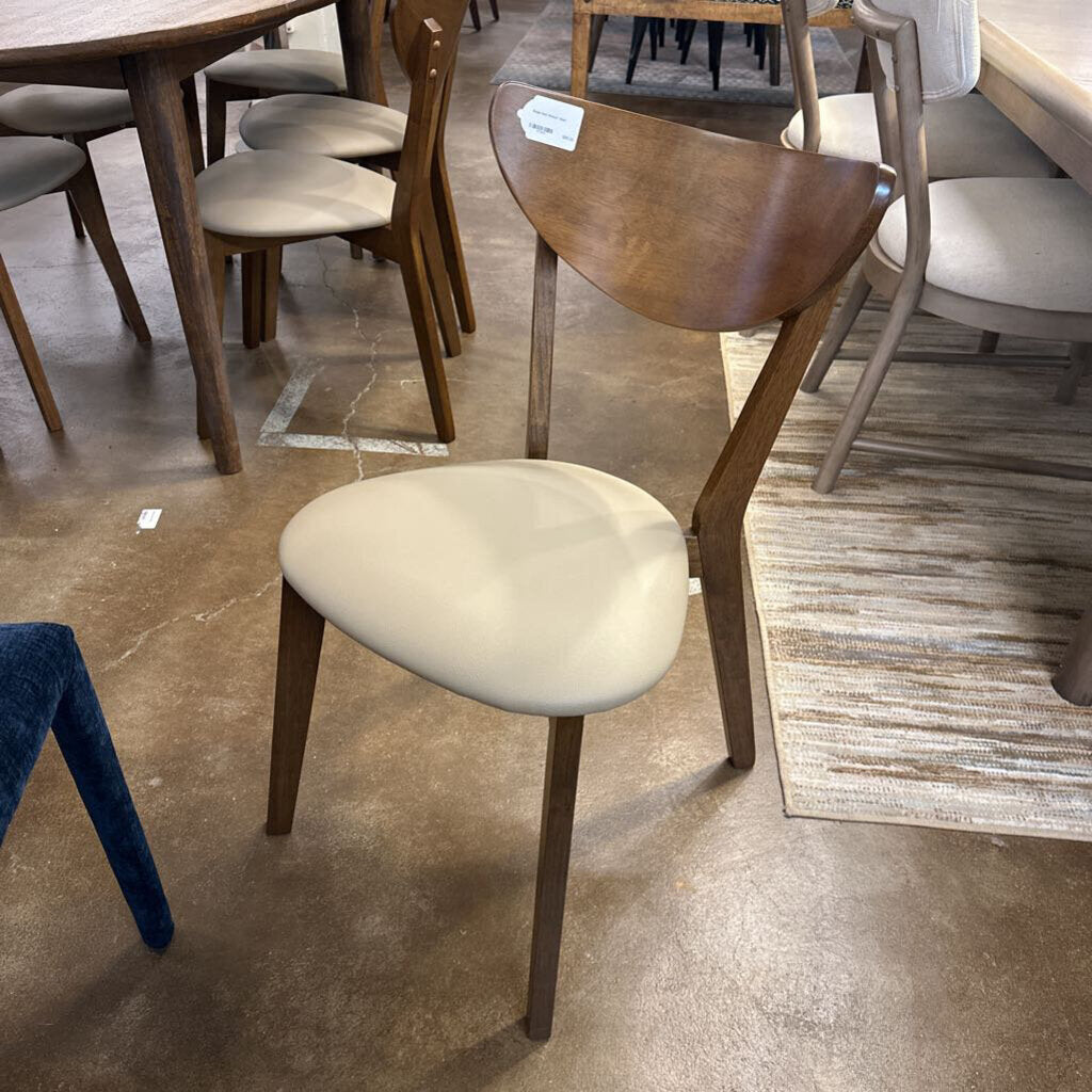 Wooden chair with a beige cushion on a tiled floor in a store setting