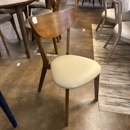 Wooden chair with a beige cushion on a tiled floor in a store setting