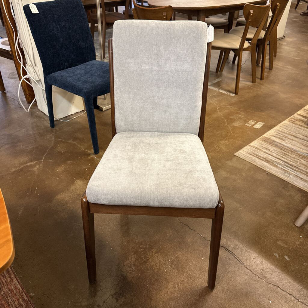 Gray upholstered chair with wooden frame on a concrete floor