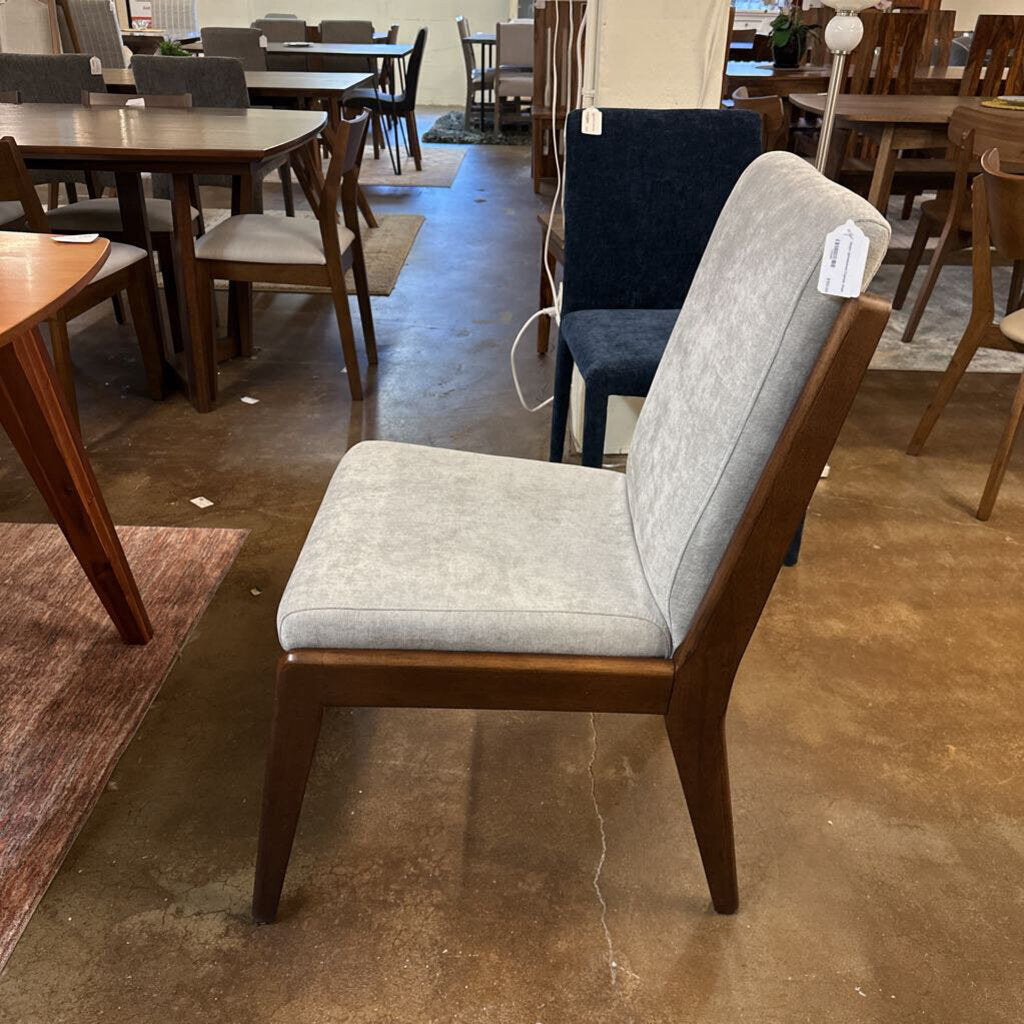 Chair with gray cushion on a floor with other furniture in the background