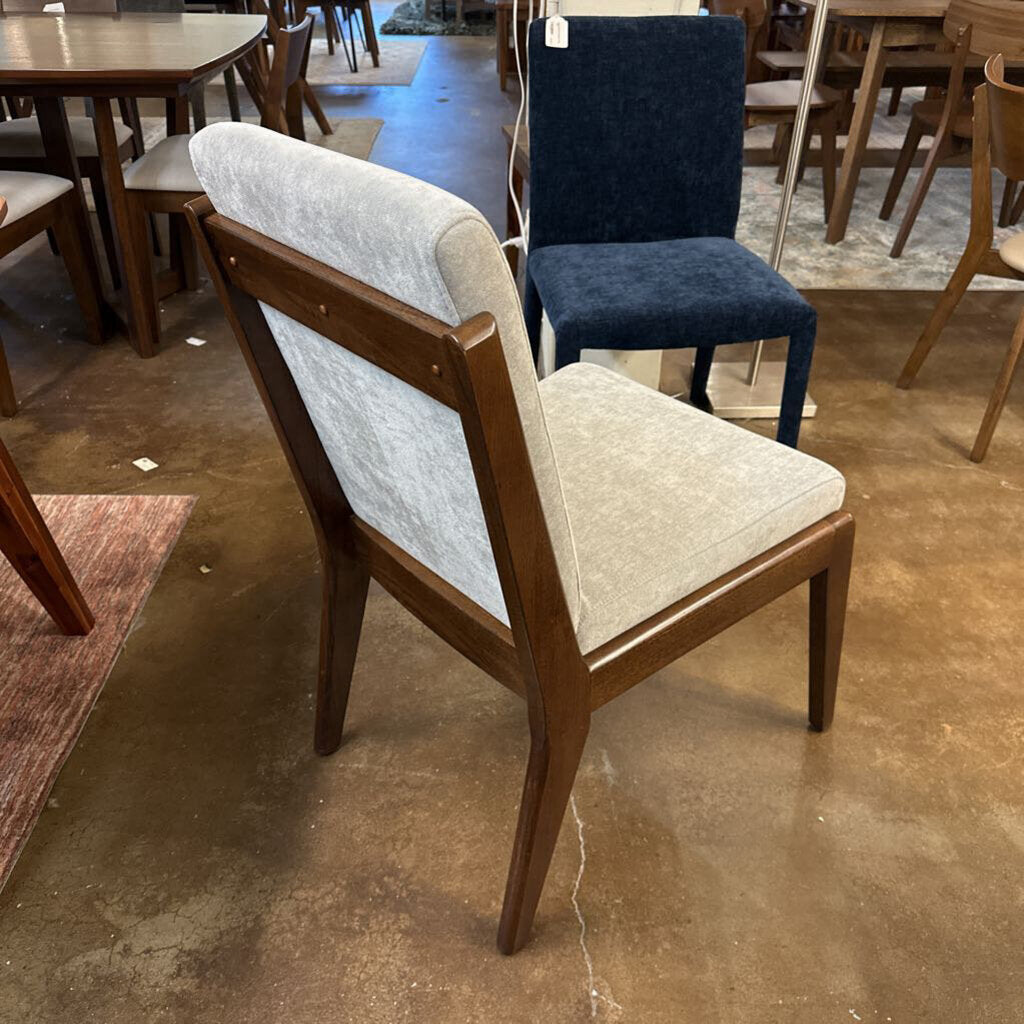 Dining chairs with wooden frames and upholstered seats in a showroom setting.