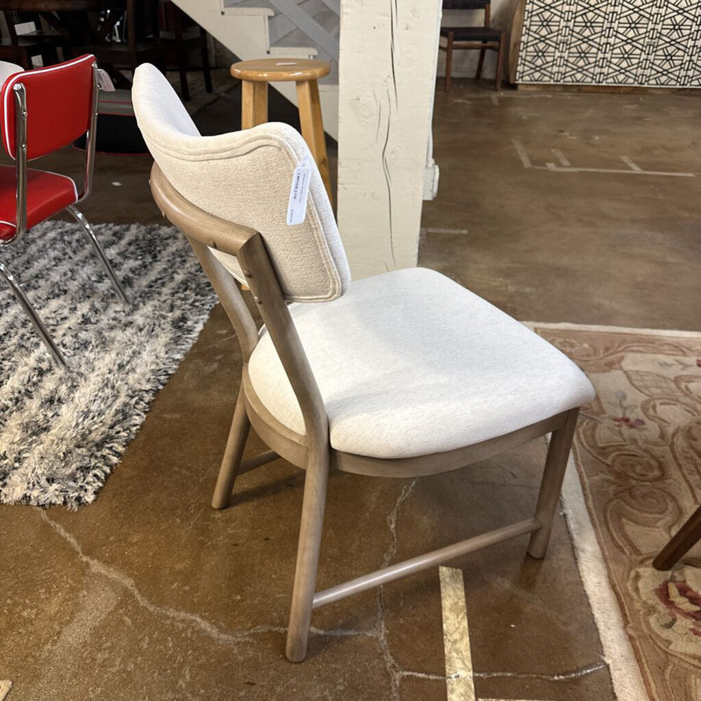 White chair with beige cushion on a stone floor in a showroom setting