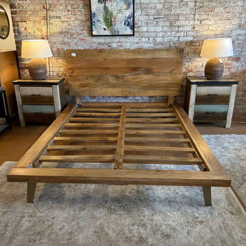 Wooden bed frame in a room with brick walls and lamps.