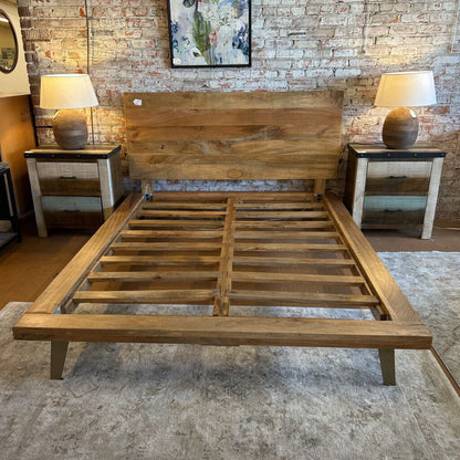 Wooden bed frame in a room with brick walls and lamps.