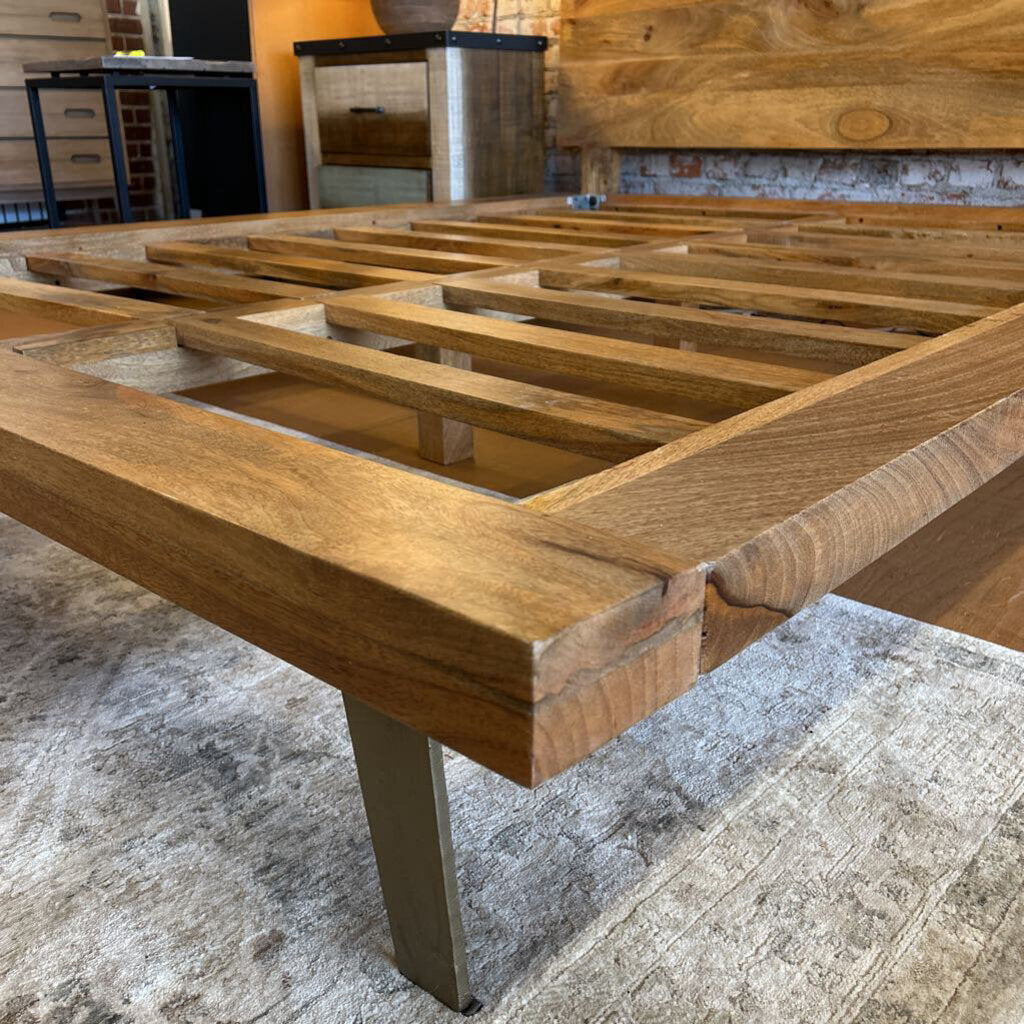 Wooden bed frame on a concrete floor with a rustic background