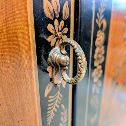 Decorative metal handle on a wooden surface with floral patterns