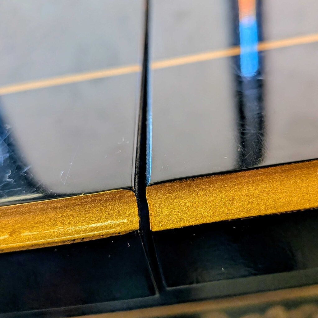 Close-up of a guitar with a gold inlay on the fretboard.