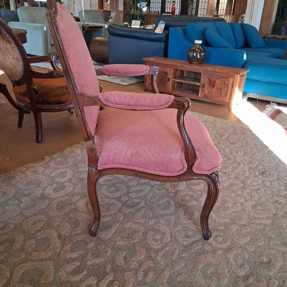 Pink upholstered chair in a room with a blue sofa and wooden coffee table.