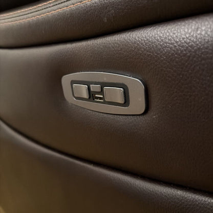 Close-up of a car door panel with control switch on brown leather