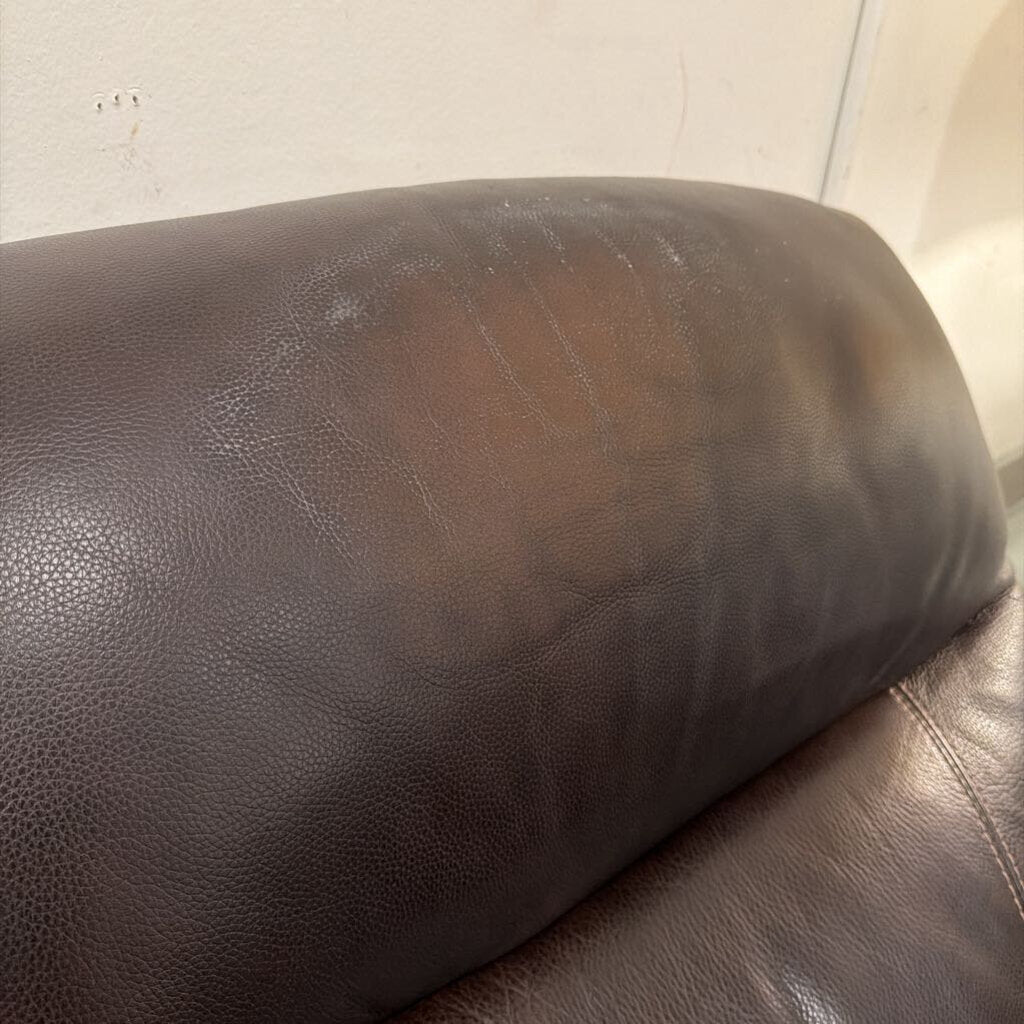 Brown leather armchair with visible wear and tear on a white background