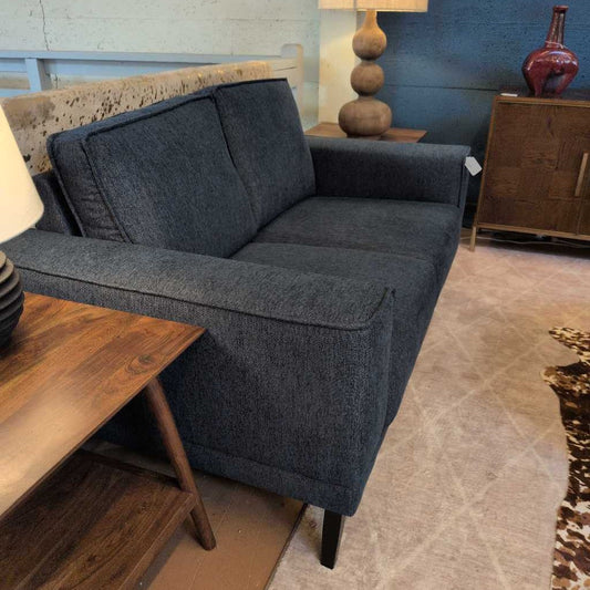 Gray sofa in a living room setting with wooden furniture and decor.