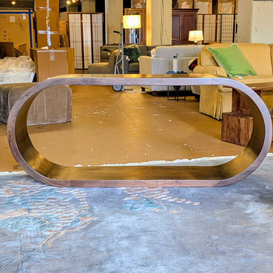 Gold oval coffee table in a showroom with furniture in the background