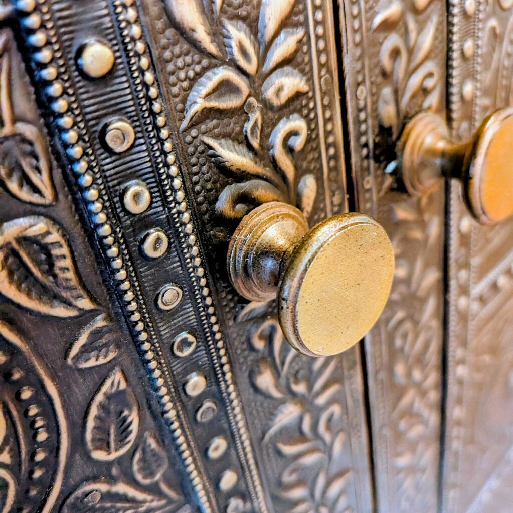 Close-up of an ornate metal door handle with intricate designs.