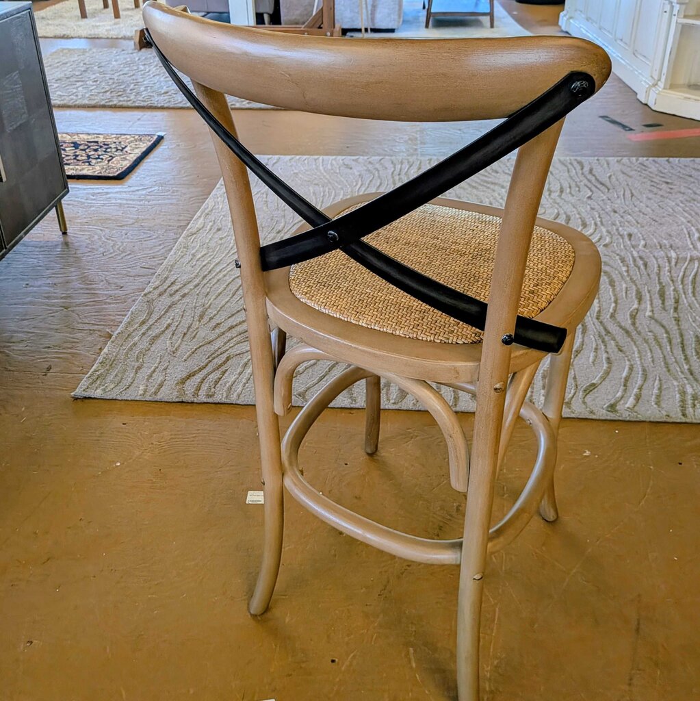 Wooden chair with a woven seat and black metal cross brace on a wooden floor.