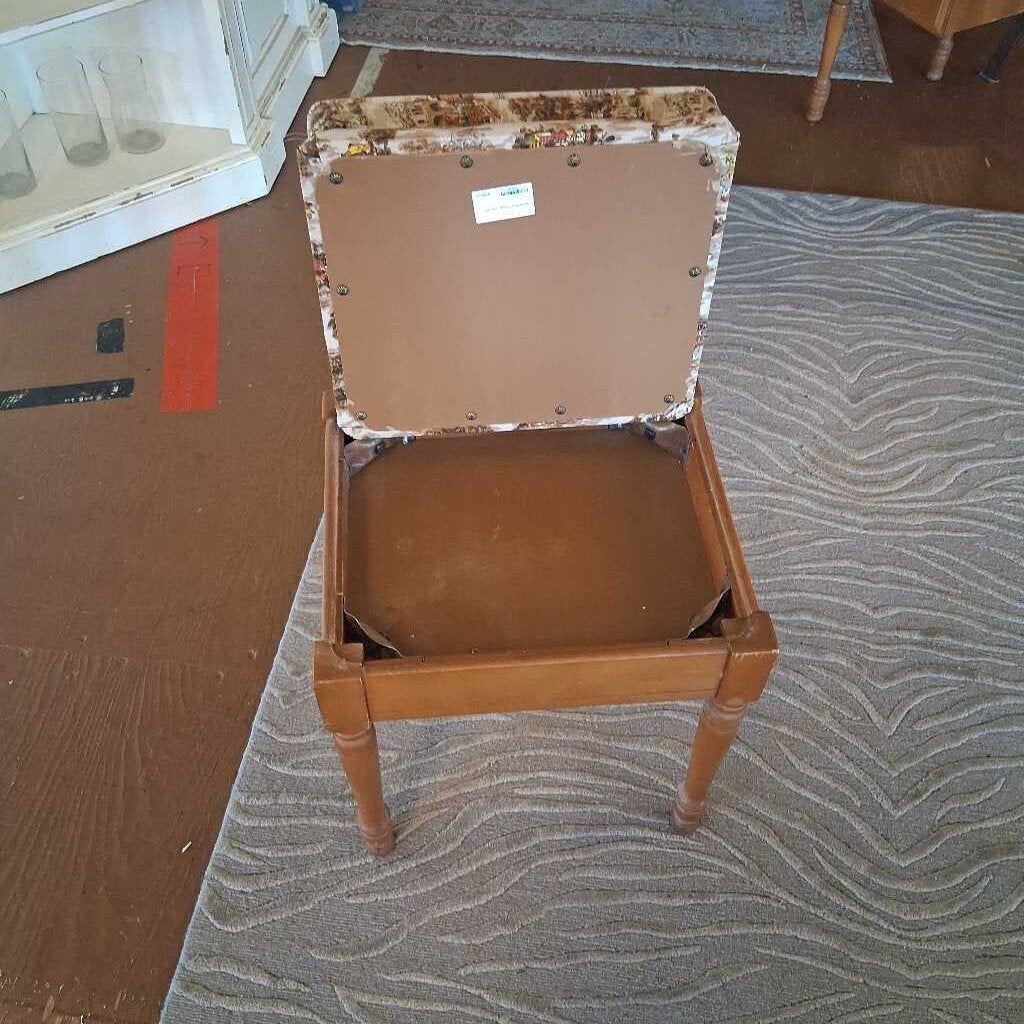 Wooden stool with floral-patterned top on a carpeted floor