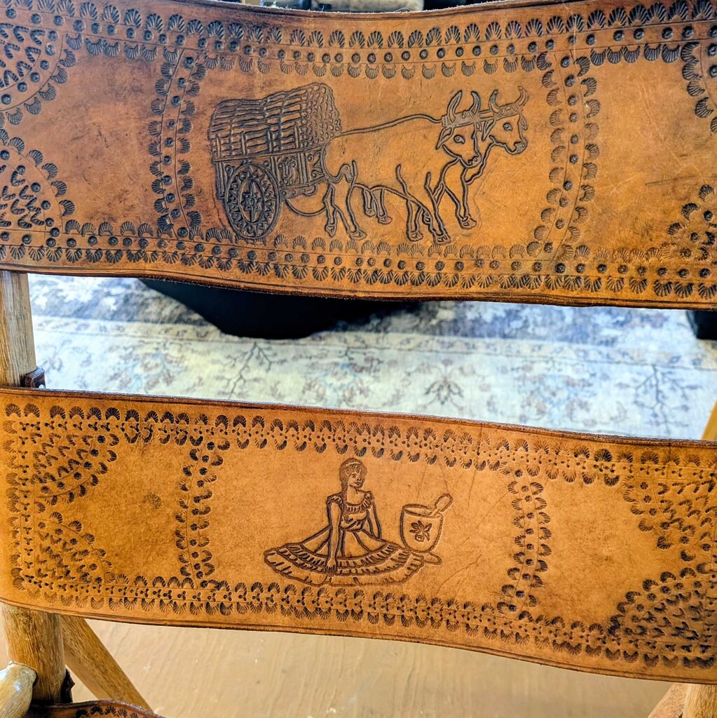 Two leather embossing tools with intricate designs on a wooden surface.