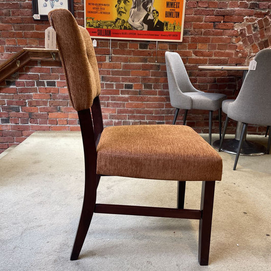 Brown upholstered chair in a room with brick walls and posters.