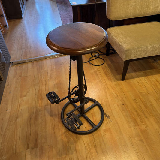 Wooden stool with metal chain mechanism on a wooden floor