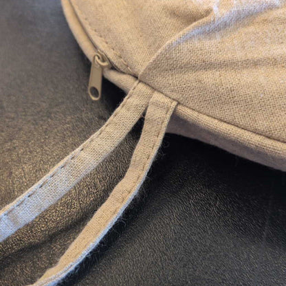 Close-up of a beige fabric pouch with a zipper on a dark surface
