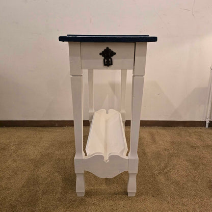 White table with a black top on a brown carpeted floor against a white wall