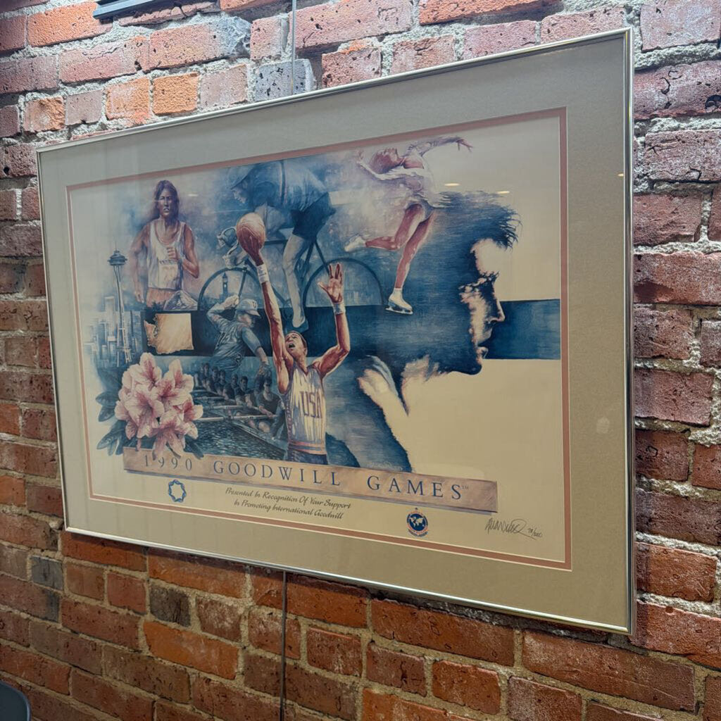 This commemorative fine art poster celebrates the 1990 Goodwill Games held in Seattle, Washington. The artwork features a dynamic multi-sport collage in a blue and earth-toned palette, depicting various athletic disciplines including basketball, cycling, figure skating, track and field, and rowing. Iconic local symbols like the Space Needle and the state of Washington are integrated into the composition.