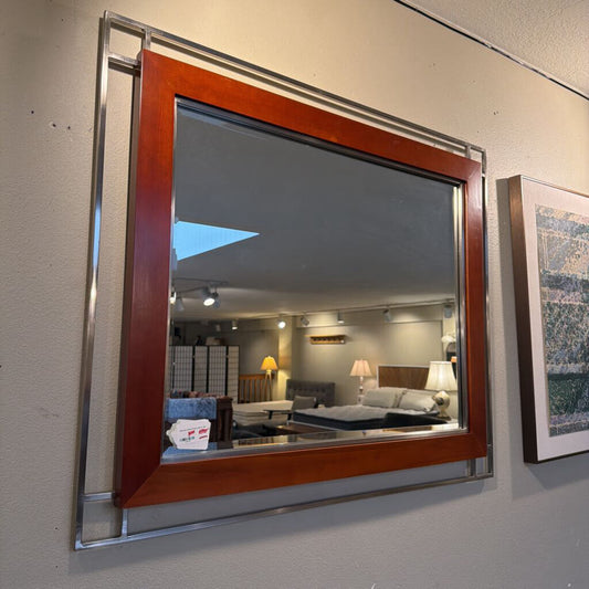 Large wall mirror with wooden frame reflecting a room interior.