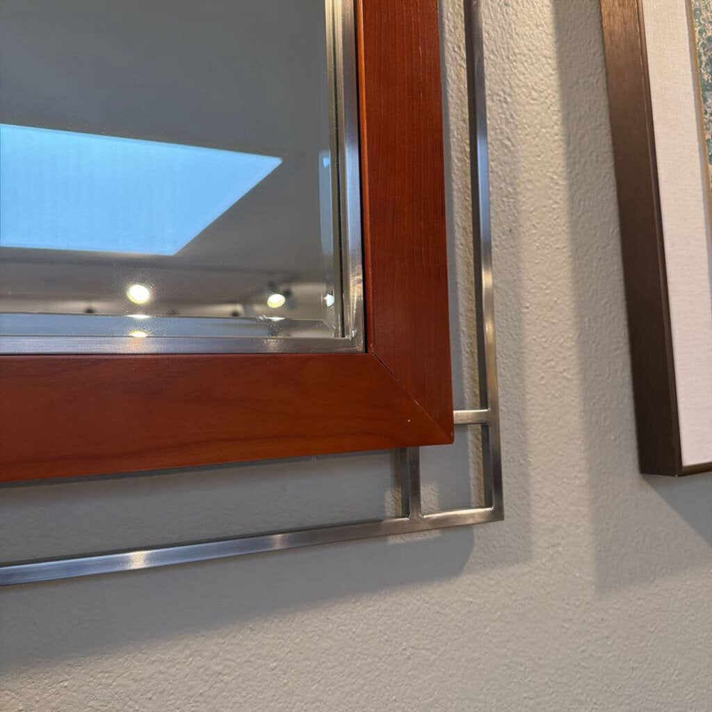 Wooden-framed mirror with metal trim on a textured wall