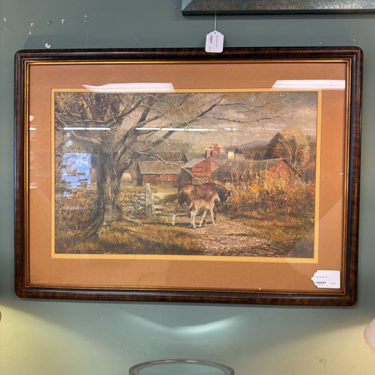 Framed painting of a pastoral scene with a deer and buildings on a wall.