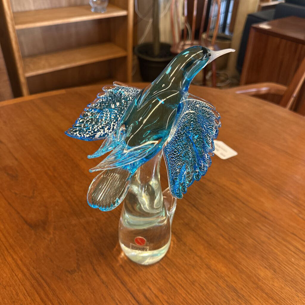 Glass hummingbird sculpture in a clear vase on a wooden table