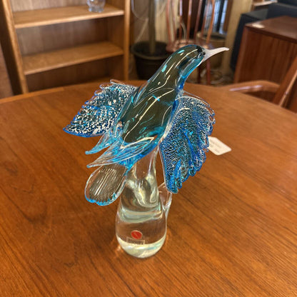 Glass hummingbird sculpture in a clear vase on a wooden table