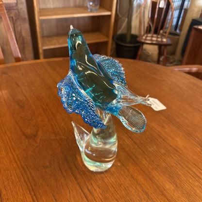 Blue glass sculpture of a fish on a wooden table