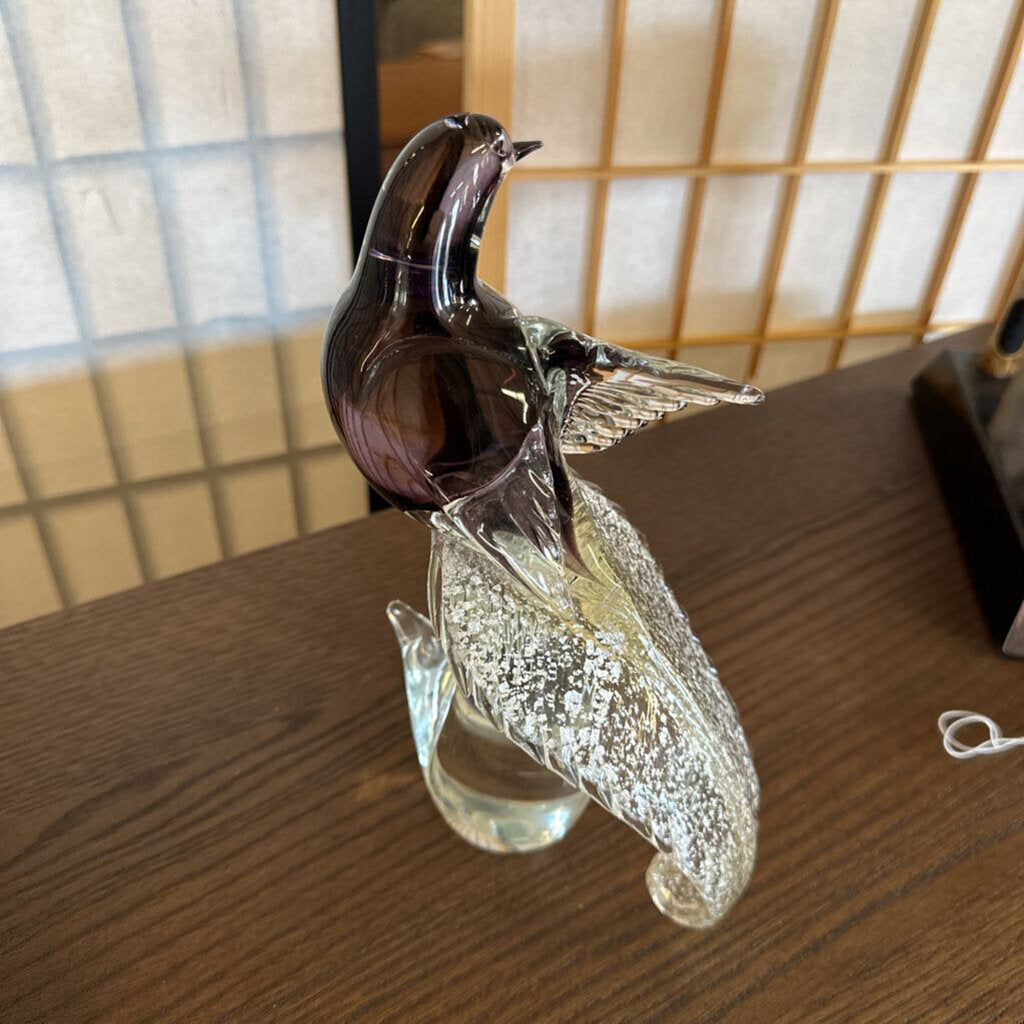 Glass sculpture of a bird on a branch on a wooden surface